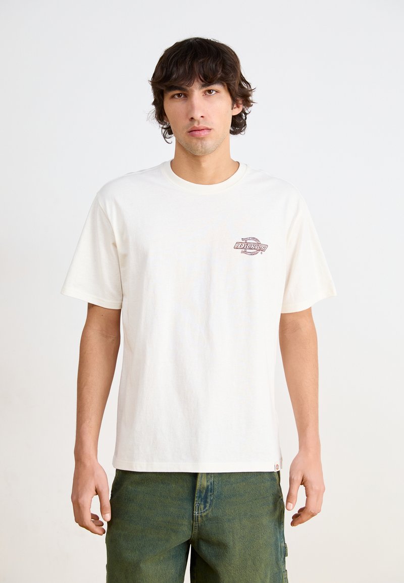 T-shirt di cotone color crema con collo tondo e maniche corte; presenta un piccolo logo stampato sulla zona sinistra del petto.