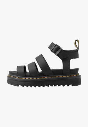 Zwarte platform sandalen met drie brede banden, verstelbare gesp en gele stiksels. Getextureerde rubberen zool met zigzagpatronen.