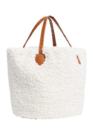 Kremowa torba typu tote o teksturowanej powierzchni z brązowymi skórzanymi uchwytami i wykończeniem, posiadająca miękką, puszystą zewnętrzną warstwę.