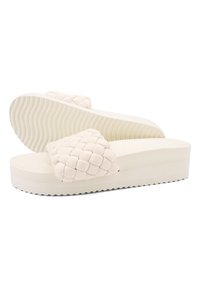 Beige platform sandals with woven textured strap, rubber sole, flat heel, and ridged bottom for traction.