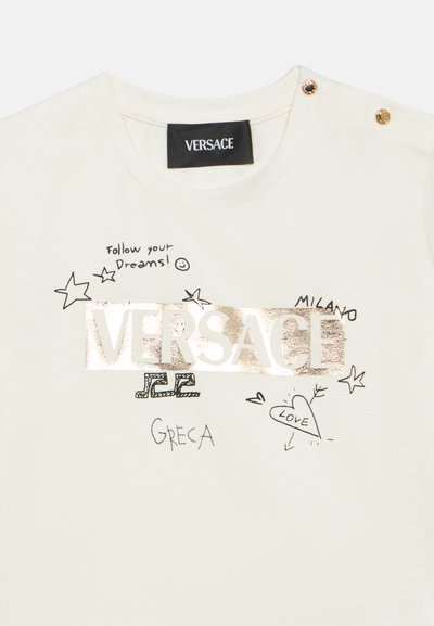 Λευκό βαμβακερό μπλουζάκι με μεταλλικό χρυσό λογότυπο "VERSACE", χειρόγραφα σκίτσα και διακοσμητικά καρφιά στον ώμο.