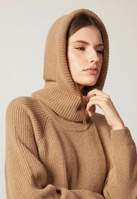Kamelhaarfarbener Strickpullover mit hohem, geripptem Kragen und Kapuze. Verfügt über einen strukturierten Stoff und eine lockere Passform mit gerippten Bündchen.