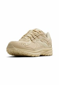 Zapatillas de running beige con parte superior sintética lisa, acentos de malla y suela acolchada. Presenta una banda texturizada para agarre y logo bordado.