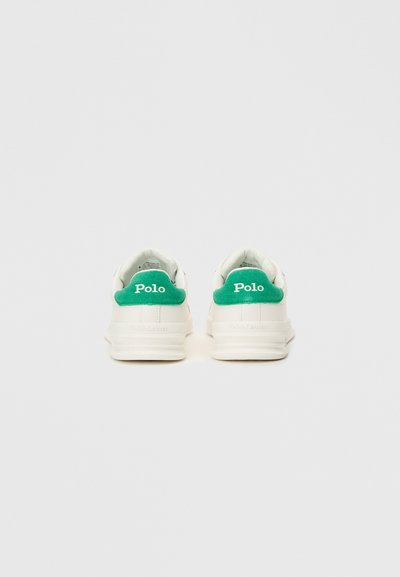 Λευκά αθλητικά παπούτσια με πράσινες σουέτ λεπτομέρειες στη φτέρνα. Διαθέτουν λογότυπο "Polo" και λεία υφή. Στρογγυλή σιλουέτα και ελαφριά σόλα.
