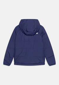 Marinblå isolerad jacka med huva, med kviltat mönster och elastiska ärmslut. Logotypen för varumärket syns på den övre ryggen.