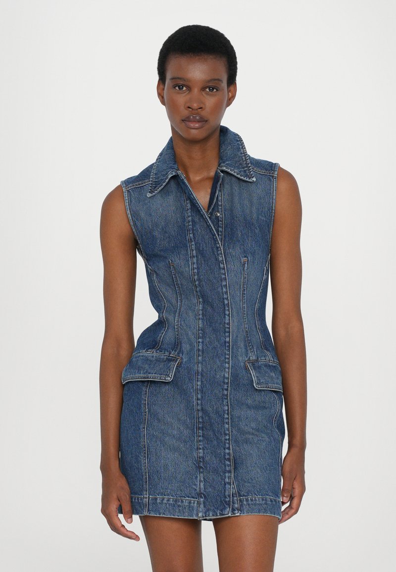 Denim ärmelloses Kleid mit Kragen, tailliertem Oberteil und zwei vorderen Taschen. Mit kontrastierenden Nähten und einem kurzen Saum.