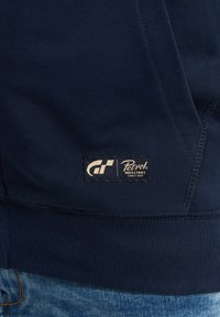 Felpa blu navy in tessuto morbido e testurizzato. Dotata di un orlo a costine e un'etichetta tessuta che mostra "Petrol Industries" con il logo.