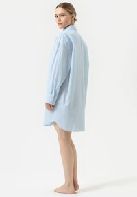 Robe chemise bleu rayée avec des manches longues, des poignets boutonnés, un col et un ourlet arrondi. Fabriquée en tissu léger et texturé.