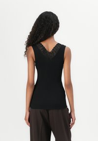 Top a maniche corte nero a coste con scollatura a V sul retro rifinita in pizzo e design aderente. Il tessuto appare morbido, conferendo un aspetto texturizzato.