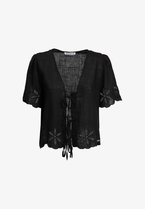 Blouse noire à manches courtes avec motifs découpés floraux sur les manches et l'ourlet, liens sur le devant, et tissu texturé par Influencer.