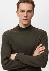 Dunkelgrünes langärmeliges Rollkragen-Shirt aus weichem, glattem Stoff mit figurbetontem Schnitt. Verfügt über einen hohen Kragen und lockere Ärmel.