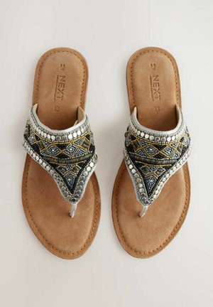 Sandales décoratives avec une semelle en daim synthétique marron, ornées de perles bleues, argentées et dorées dans un motif géométrique. Design plat, avec un entre-doigts.