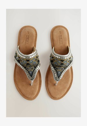 Sandalias decorativas con plantilla de ante sintético marrón, adornadas con cuentas azules, plateadas y doradas en un patrón geométrico. Diseño plano, con separación para los dedos.