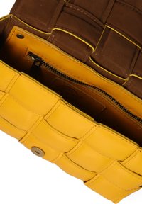 Borsa a tracolla in pelle intrecciata gialla con pattina aperta, tasca con cerniera visibile e rivestimento interno in marrone cucito.