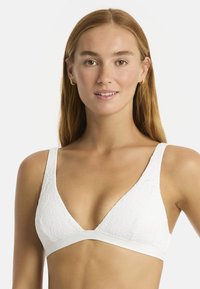 Weißer Triangel-Bralette mit floralem Präge-Muster, ausgestattet mit breiten Trägern und einem glatten Unterbund. Der Stoff wirkt weich und strukturiert.
