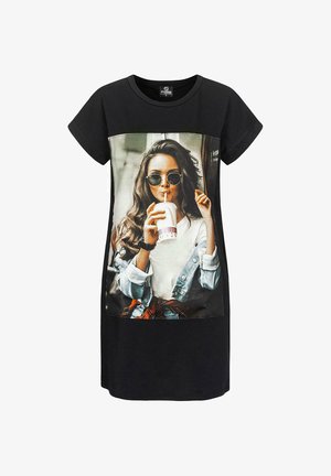 Fekete pólóruha, elöl egy napszemüveget viselő nő fotónyomtatásával, aki italt tart a kezében. Puha anyag, laza fazon, rövid ujjú.