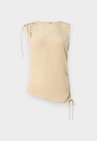 Top beige senza maniche con orlo asimmetrico, caratterizzato da una parte arricciata sulla spalla e lacci regolabili su un lato. Tessuto morbido.
