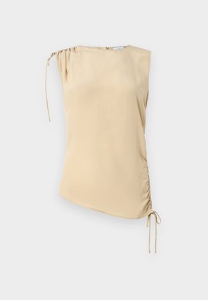 Beige ermeløs topp med asymmetrisk kant, med en samlet seksjon på skulderen og justerbare bånd på den ene siden. Glatt tekstur.