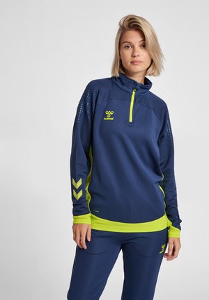 Marineblauwe sportpullover met een halve rits, gele accenten en een gestippeld patroon op de schouders. De stof lijkt textuur te hebben voor ademend vermogen.