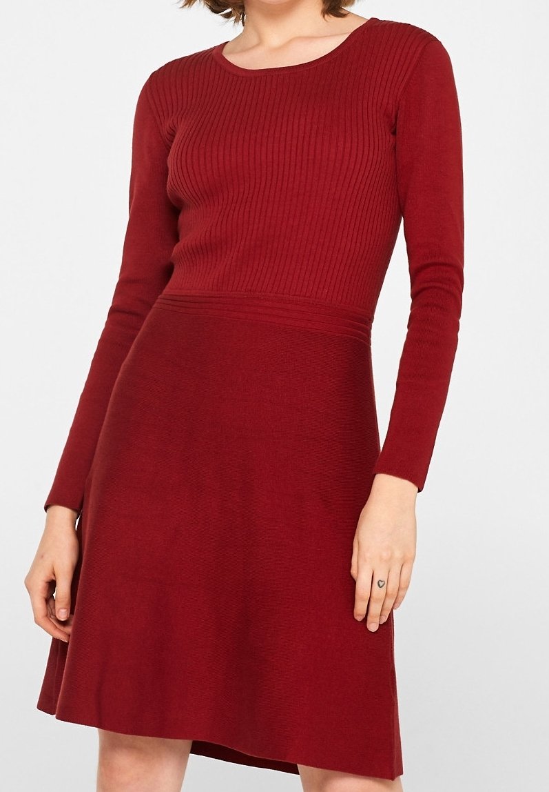 Femme portant une robe rouge en maille côtelée à manches longues, avec un col rond et une jupe trapèze.