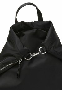 Sac à dos noir en nylon avec fermeture éclair supérieure, garnitures argentées et une boucle de suspension. Texture lisse et design minimaliste.