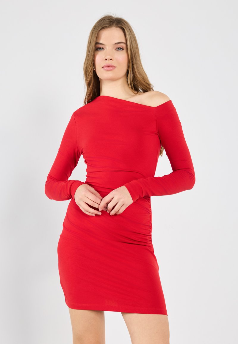 Rode, nauwsluitende jurk met lange mouwen en een asymmetrische off-shoulder halslijn. Gemaakt van soepele stof met geplooide details bij de taille.