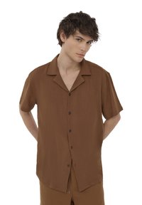 Camicia a maniche corte realizzata in un tessuto marrone testurizzato, con una chiusura a bottoni sul davanti, colletto a punta e un taglio rilassato.