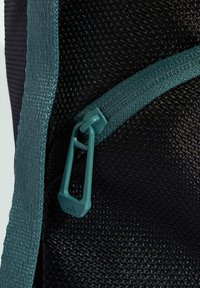 Tejido negro texturizado con cremallera y correa en azul verdoso. El tirador de la cremallera tiene un diseño de bucle con un detalle de logo. Vista en primer plano centrándose en el hardware.