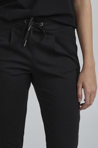 Svarta byxor med dragsko i midjan, med två framfickor och ett mjukt, stretchigt tyg. Enkel design utan synliga mönster eller detaljer.
