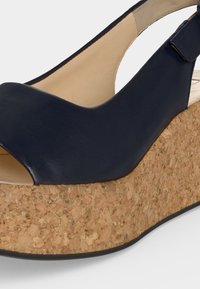 Δερμάτινο σάνταλ με βαθύ μπλε χρώμα, πλατφόρμα από φελλό, ανοικτή μύτη και ρυθμιζόμενο λουράκι αστραγάλου.