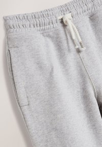 Light grey sweatpants with an elastic waistband and drawstring, featuring side pockets and a soft, textured fabric.