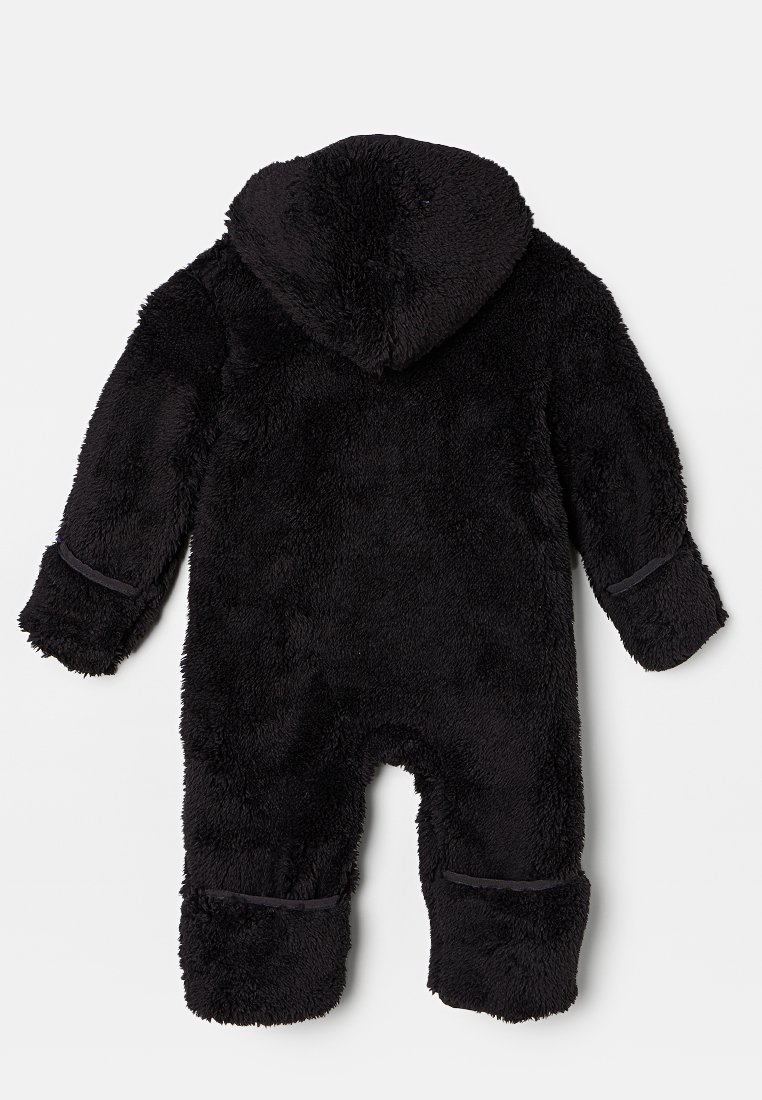 Mono de forro polar negro con capucha, que presenta una textura suave y esponjosa, mangas largas y puños elásticos en las muñecas y tobillos.