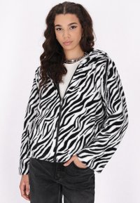 Giacca in peluche a fantasia zebratica con zip integrale, cappuccio e texture morbida. Il design in bianco e nero ne esalta l'aspetto audace.