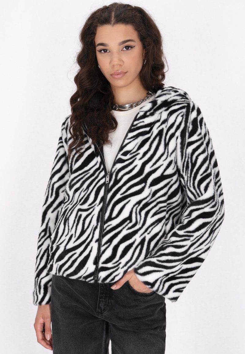 Giacca in peluche a fantasia zebratica con zip integrale, cappuccio e texture morbida. Il design in bianco e nero ne esalta l'aspetto audace.