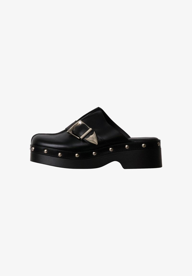 Sabot en cuir noir à enfiler avec boucle argentée et rivets métalliques ronds le long de la semelle épaisse, vue latérale en angle sur fond blanc.