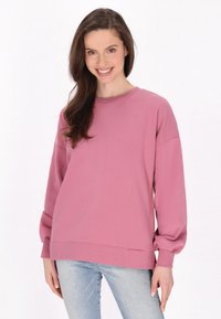 Lyserød sweatshirt med lange, voluminøse ærmer og rund halsudskæring. Stoffet ser blødt ud, og den har en afslappet pasform med struktureret kant.