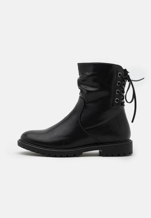 Sort læderstøvle til midtkalv med rund tå, kraftig sål og snøredetalje bag på anklen mod en ensfarvet baggrund.