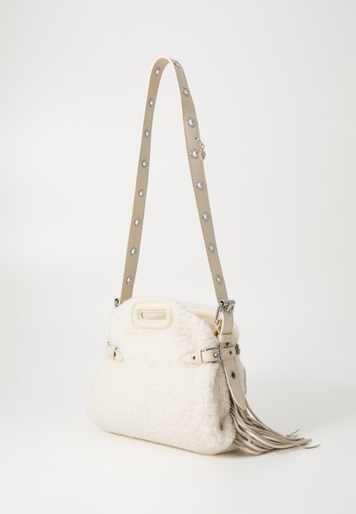 Borsa in finta pelliccia bianca con tracolla beige decorata da borchie argentate, dalla forma strutturata e con un dettaglio di frange su un lato.