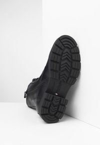 Zwarte leren laars met een getextureerde rubberen zool. Voorzien van een zijrits en versterkte stiksels. De zool heeft een robuust profiel.