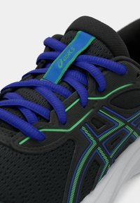 Μαύρο αθλητικό παπούτσι με μπλε κορδόνια και σχέδιο με πράσινες λεπτομέρειες. Υφή στην επάνω πλευρά με σχέδιο που μοιάζει με δίχτυ και επενδεδυμένη γλώσσα.
