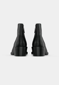 Melnas ādas potītes zābaki ar gludu virsmu, sašaurinātu formu un kvadrātveida papēžiem. Aprīkoti ar rāvējslēdzēju aizmugurē, kas nodrošina vieglu uzvilkšanu.