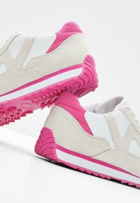 Sneakers in suede beige e sintetico bianco con dettagli rosa. La suola in gomma testurizzata presenta un motivo di battistrada distintivo per una migliore aderenza.