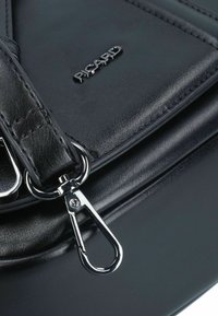 Schwarze Lederhandtasche mit strukturierter Oberfläche, silbernem Zubehör und einem Verschlussdetail. "PICARD"-Logo auf der Vorderseite geprägt.