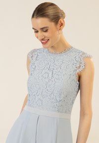 Hellblaues Spitzenkleid mit Blumenmuster, ärmelloses Design, Wellen-Halsauschnitt und festem Taillenbund. Glatte Textur, elegante Silhouette.