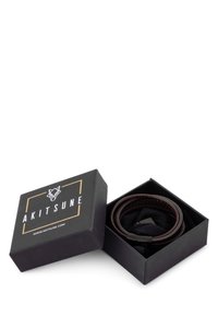 Brown leather bracelet inside a black box with a logo. The box has a square shape and gold accents, featuring a black fabric interior.
