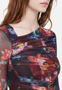 Šaty s květinovým potiskem s burgundským základem, průhlednými dlouhými rukávy, draped texturou a širokým výstřihem, které se vyznačují živými barvami a vzory.