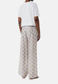 Biała, krótka bawełniana koszulka z krótkim rękawem zestawiona z luźnymi spodniami w fioletowo-zielony wzór kwiatowy, z elastyczną talią.