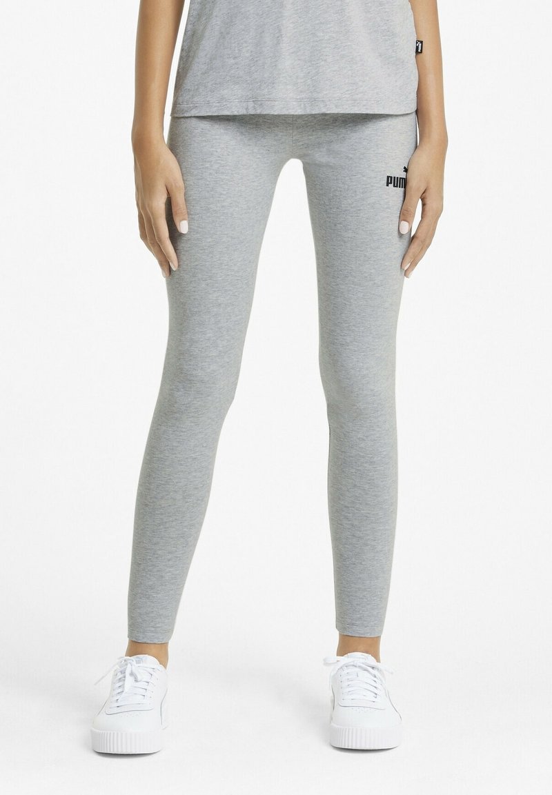 Grå leggings i stretchmaterial med en slät yta. Utrustad med en logotyp på sidan och tillsammans med vita sneakers.