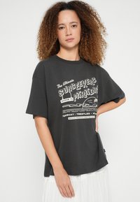 Tumehall lühikeste varrukatega T-särk, millel on valge retrostiilis graafiline tekst ja rannamaastik. Pehme puuvillane materjal, mugav lõige.