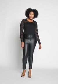 Haut noir à manches longues avec détail en dentelle, associé à un pantalon taille haute en simili cuir noir et des sandales à talons transparents. Textures lisses.